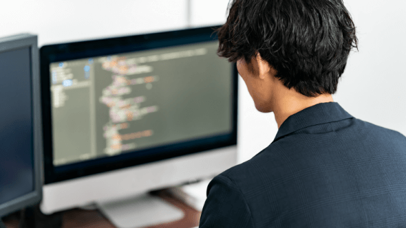 パソコンでコードを書く男性